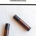 Two brown roller bottles with black caps rest on a light surface, labeled ROLLER BLEND FRANKINCENSE. Ideal for those interested in crafting a DIY Frankincense roller blend, these bottles offer an inviting canvas for your aromatic creations.