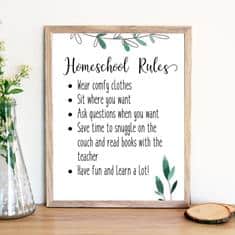 A framed sign titled Homeschool Rules rests on a wooden surface beside a vase of flowers. The rules&mdash;comfy clothes, ask questions, read on the couch, and have fun&mdash;are topped with green leaf illustrations. Perfect for bright spaces where you might use free solar system printables to spark curiosity.